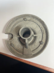 Underside of used medium gas stove burner head showing inlet tube, locating pin and cast markings